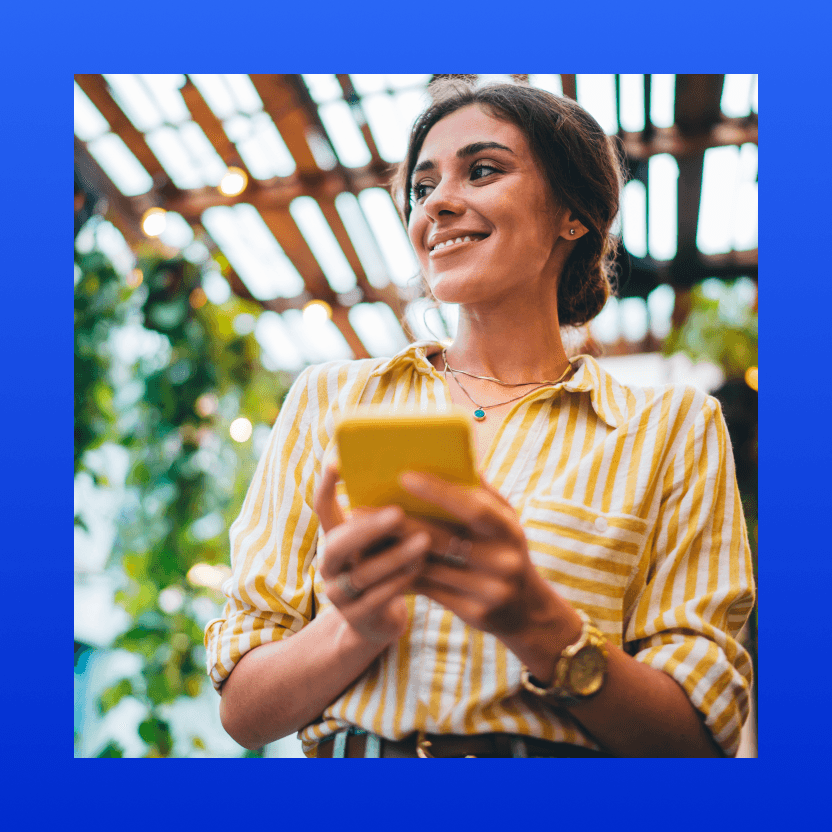 Imagem com moldura azul e uma mulher sorrindo com celular na mão olhando para o lado.