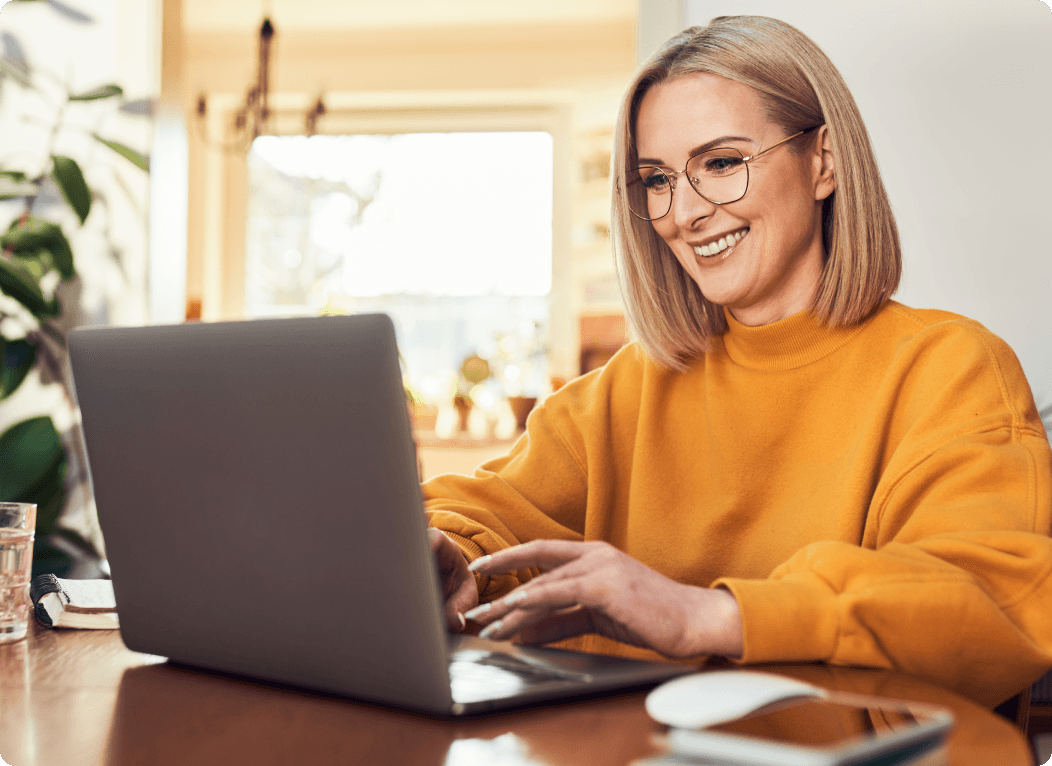 Imagem de uma mulher sorrindo usando um laptop